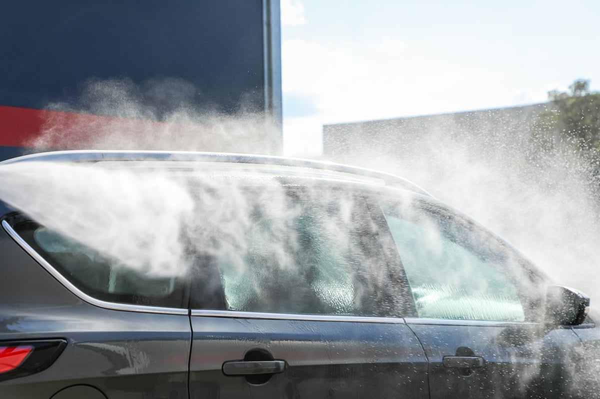 Car being thoroughly cleaned with a powerful high-pressure jet